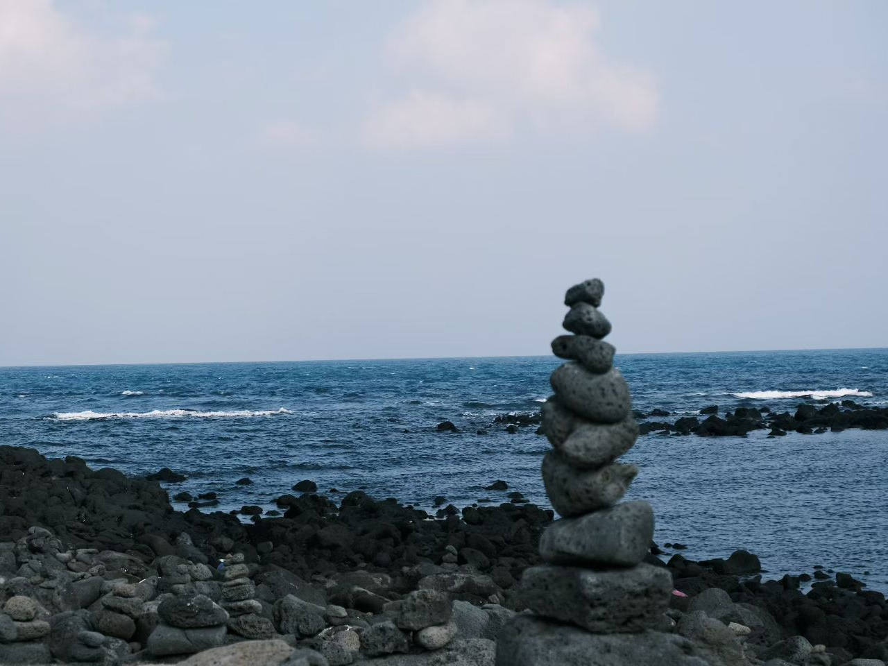 Stacked stones by the sea with water beyond