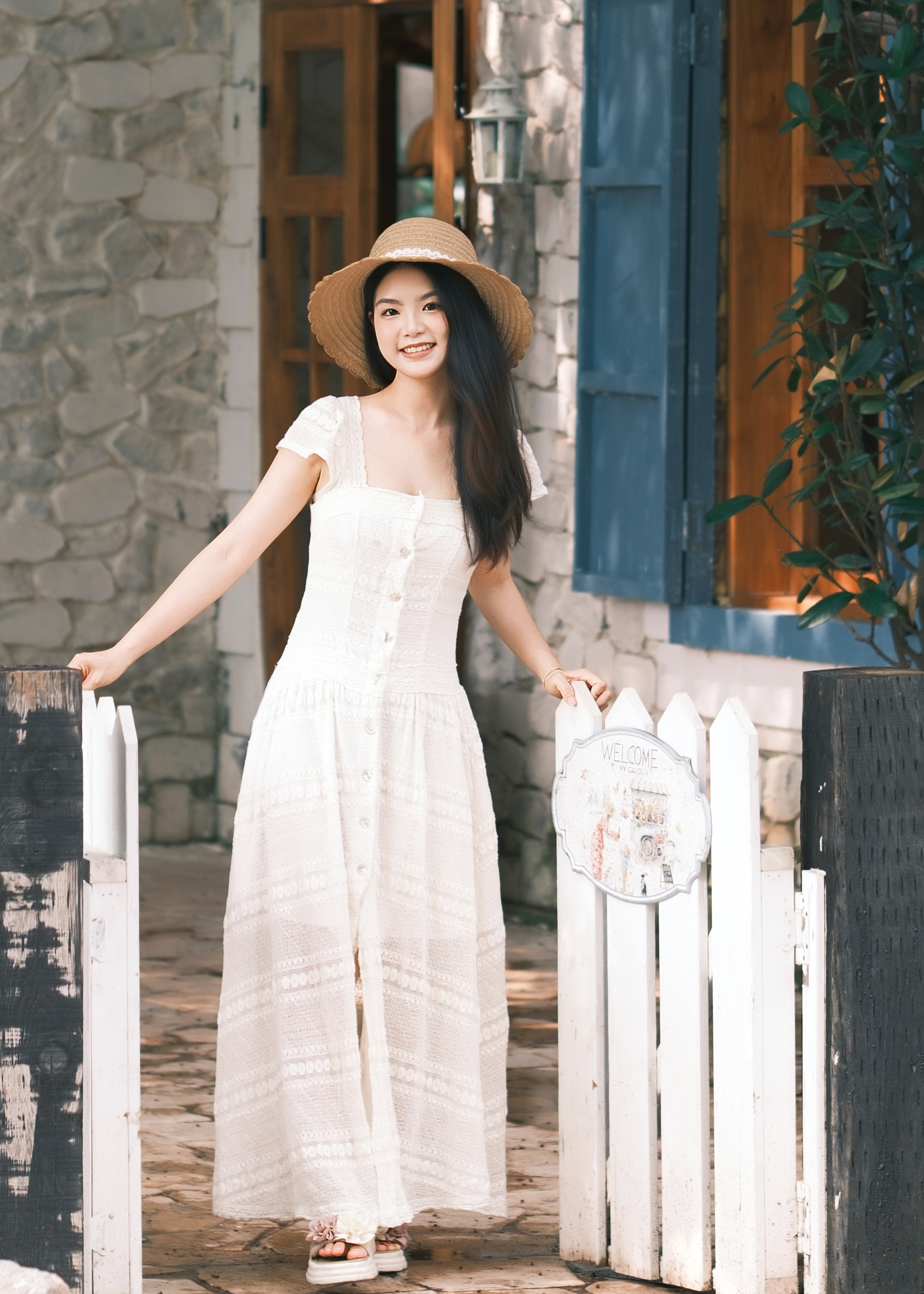 Outdoor portrait in a white dress beside a wooden gate
