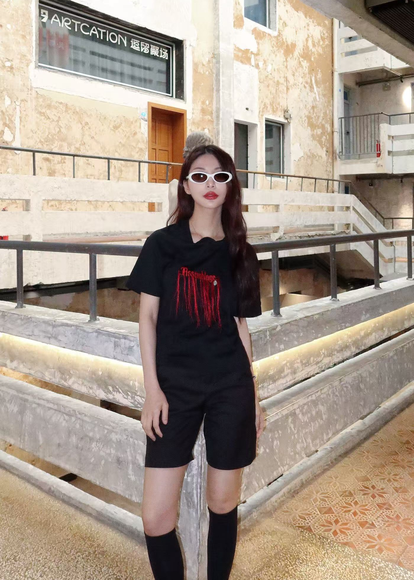 Portrait in black with sunglasses against a stone wall