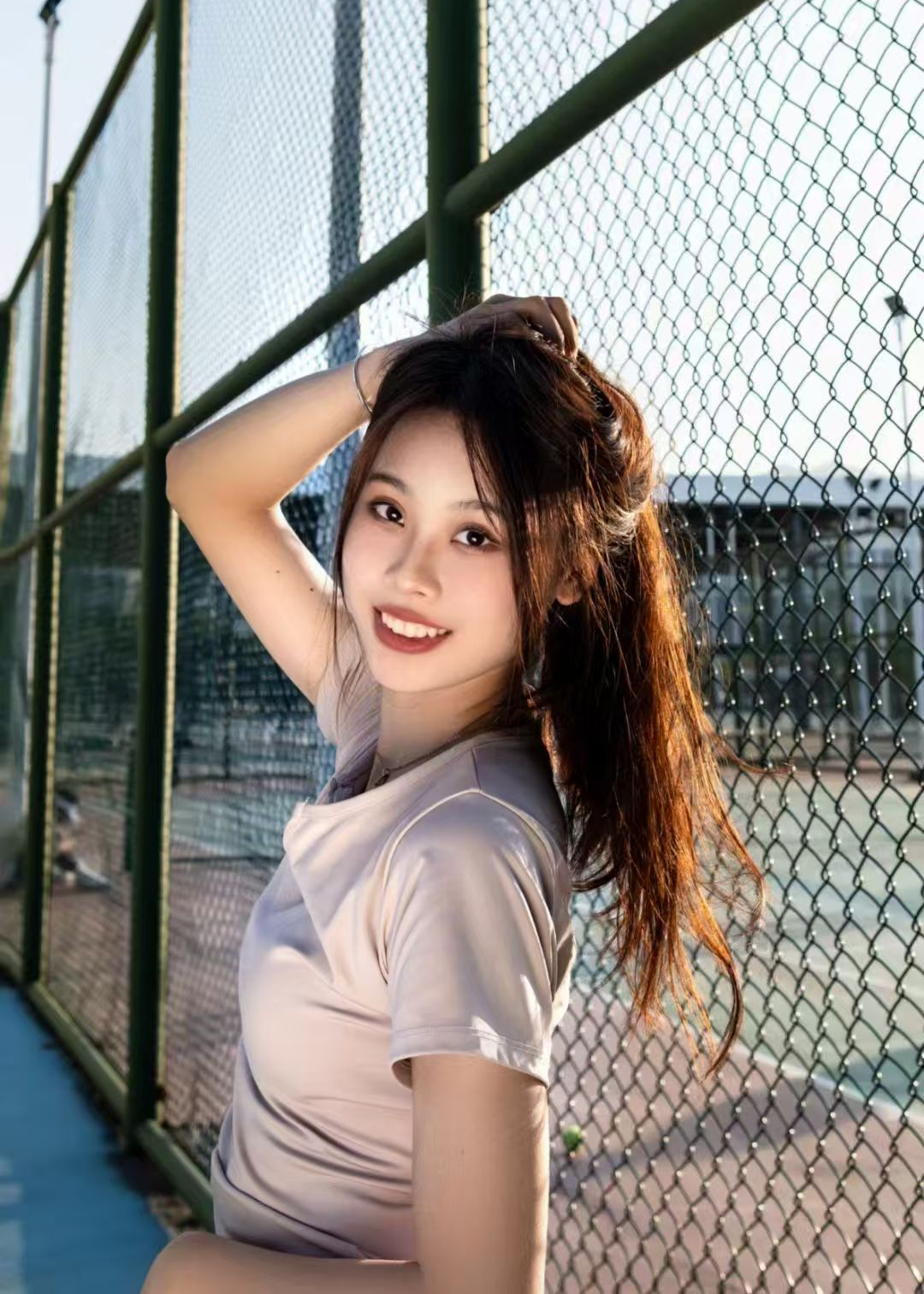 Backlit portrait beside a wire fence